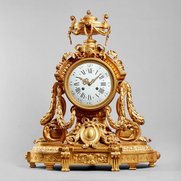 A French ormolu mantel clockIn the Louis XVI style, circa 1885The drum-shaped case surmounted by a swagged urn, with ribbon-tied surmount, on a steppe