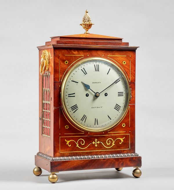 A Regency mahogany and brass-inlaid bracket clockThe case with a chamfered pediment surmounted by a pineapple finial, above the 8in. convex white pain