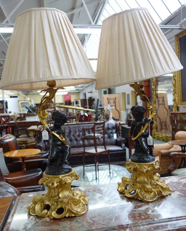 A pair of French ormolu and bronze table lamps, circa 1870, with shades formed as Bacchic putti with vine garlands in their hair, holding cornucopia s