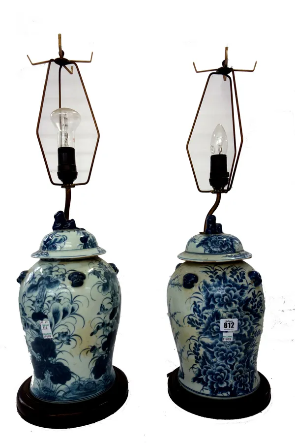 A pair of Chinese blue and white vase and covers (converted to table lamps), each with relief masks, decorated with flowers and prunus against a balus