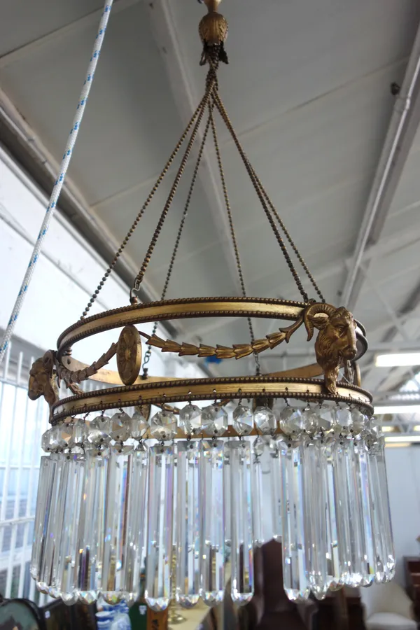 A brass and glass chandelier, late 19th/early 20th century, the open circlet frame cast with floral swags and rams head masks, hung with cut glass dro