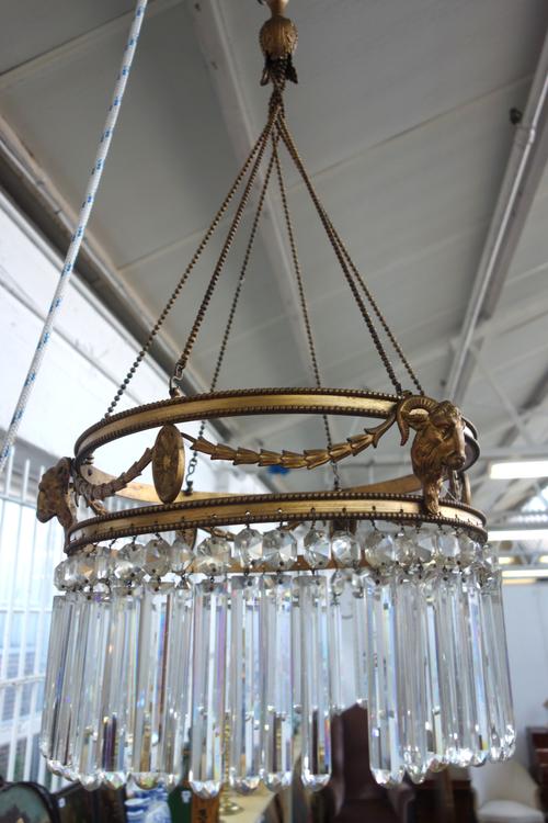 A brass and glass chandelier, late 19th/early 20th century, the open circlet frame cast with floral swags and rams head masks, hung with cut glass dro