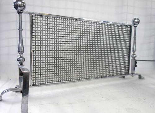 An early 20th century polished steel and wire mesh fire guard, of low rectangular form with two spherical finials on two shaped feet, 85cm wide x 37cm