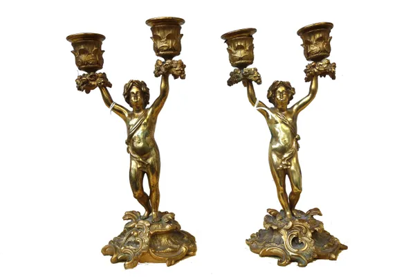 A pair of figural bronze twin branch candelabra, late 19th century, each putti figure on a rococo style base, 24.5cms high (2).