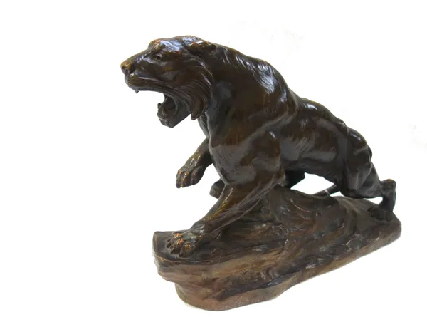 A bronzed terracotta model of a tiger, early 20th century, indistinctly signed and modelled on a naturalistic rocky base, 63cm wide.