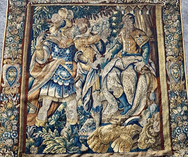 A verdure tapestry, late 17th Century, woven in wools, depicting a cuirassed warrior wearing plumed helmet and two other figures, within foliate borde
