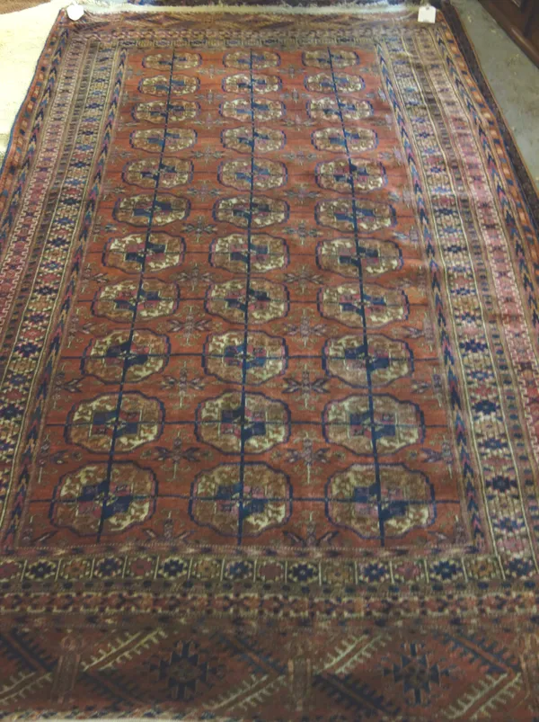 A Tekke Turkman rug, the madder field with three columns of eleven guls, supporting bee crosses, various border, skirt ends, 234 x 139cm.