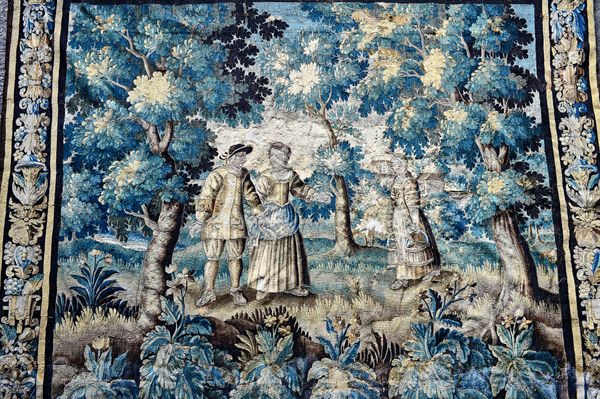 A verdure tapestry, late 17th Century, woven in coloured wools, depicting a couple in a wooded clearing, a maid to their left approaching, the base wi