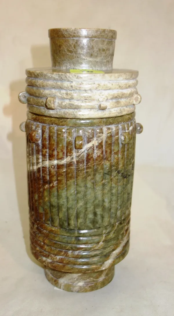 A Chinese soapstone urn and cover of ribbed cylindrical form, on narrow cylindrical base, of mottled grey/brown tone, the rim and cover set with a ser