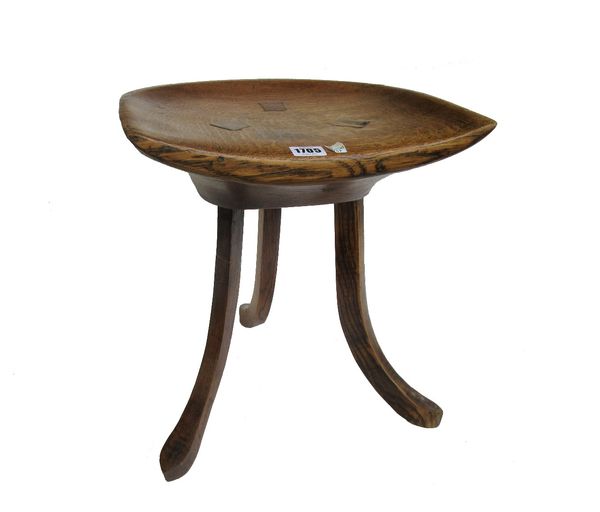 Liberty; an oak Thebes stool, with dished solid seat on three splayed supports, 35cm wide x 39cm high.