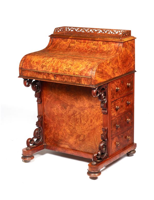A mid-Victorian figured walnut Davenport, with fitted interior over four side drawers and opposing cupboards on pierced scroll brackets, 63cm wide x 9