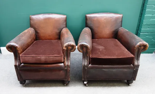 A pair of mid-20th century French brass studded brown leather upholstered easy arm chairs on turned supports, 85cm wide x 80cm high x 71cm deep.