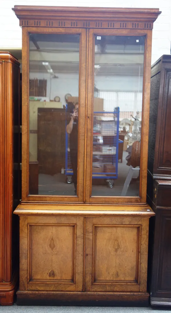 A Victorian figured oak bookcase cabinet; the pair of glazed doors over panelled cupboards on plinth base 116cm wide x 240cm high x 44cm deep.