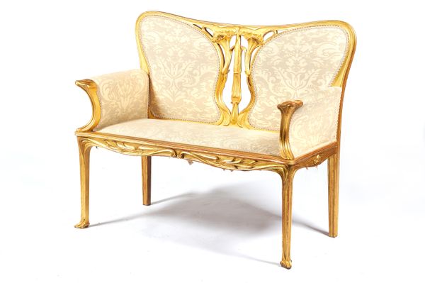 Attributed to Georges de Feure, circa 1900, a French gilt framed two seat sofa, with stylised carved floral decoration, 115cm wide x 98cm high x 53cm