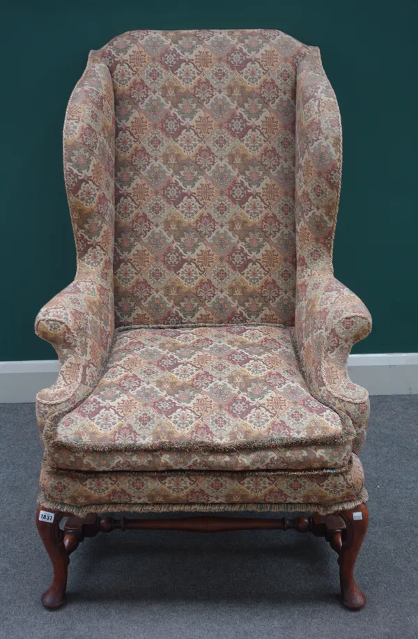 An early 18th century style walnut framed wingback armchair on cabriole supports, united by block and turned stretcher, 74cm wide x 113cm high x 90cm