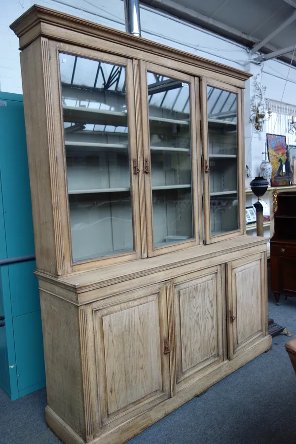 A Victorian bleached oak triple section bookcase cabinet, on plinth base, 189cm wide x 230cm high x 50cm deep.