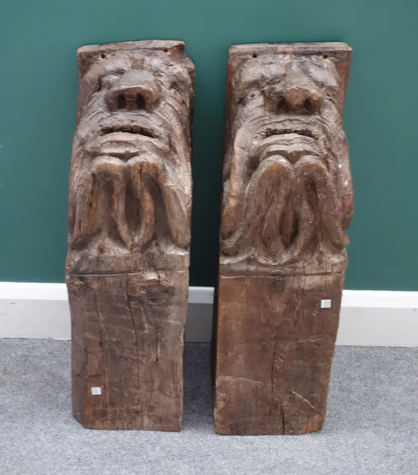 A pair of 18th/19th century pitch pine ceiling bosses, relief carved with grotesque masks, each 22cm wide x 26cm high x 73cm deep, (2).