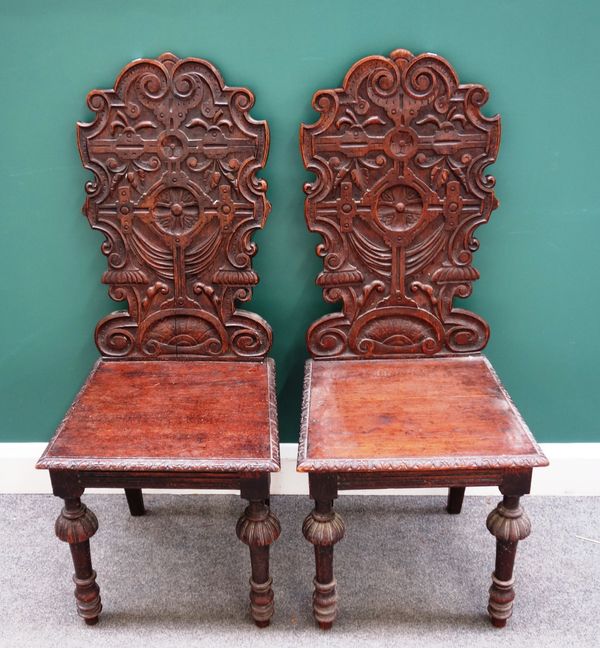 A pair of 17th century style oak hall chairs, with carved back and turned supports, 47cm wide x 110cm high x 50cm deep.