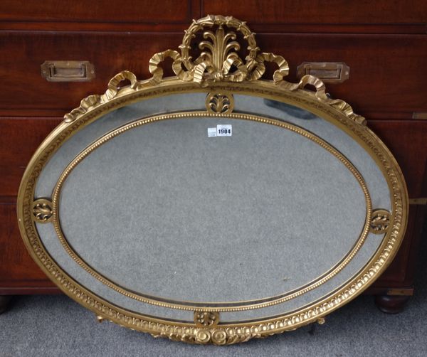 A George III style gilt framed oval wall mirror, with ribbon tied crest and segmented frame, 87cm wide x 82cm high.