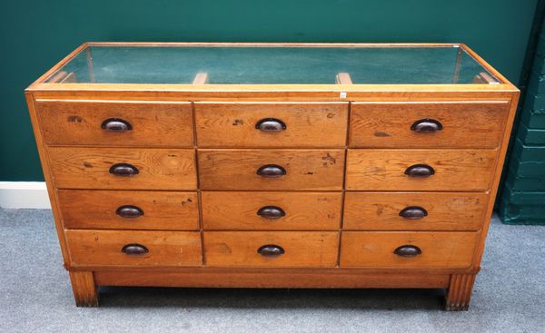 A mid-20th century oak framed haberdashery cabinet, with three rows of four graduated drawers, on block feet, 153cm wide x 99cm high x 59cm deep.