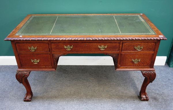 An early 20th century oak writing desk, the leather inset gadrooned top over five frieze drawers, on claw and ball feet, 137cm wide x 77cm high x 68cm