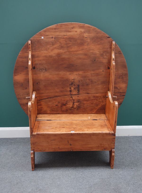 A 19th century North European pine monk's bench, with flip-up circular top and box seat, 133cm diameter x 75cm high, 147cm open.