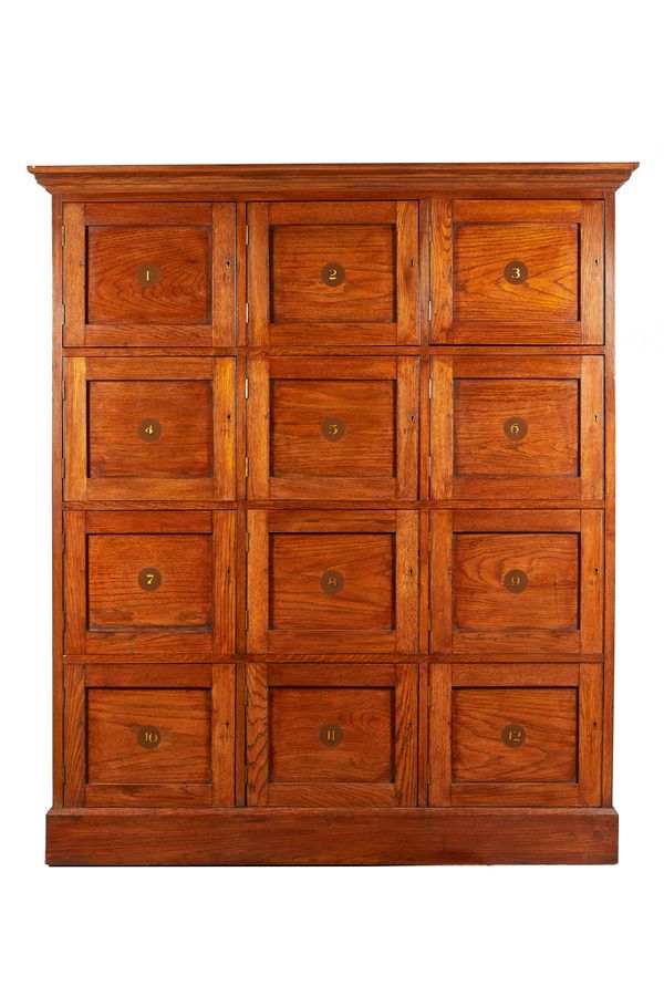 An early 20th century and later oak locker cabinet, of three rows of four drawers, on plinth base, 147cm wide x 178cm high x 43cm deep.  Illustrated