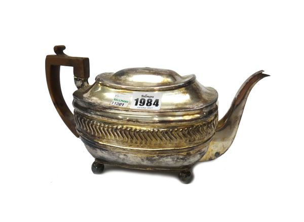 A George III silver teapot, of curved rectangular form, with flush hinged lid (the finial damaged), the body with embossed decoration raised on four b