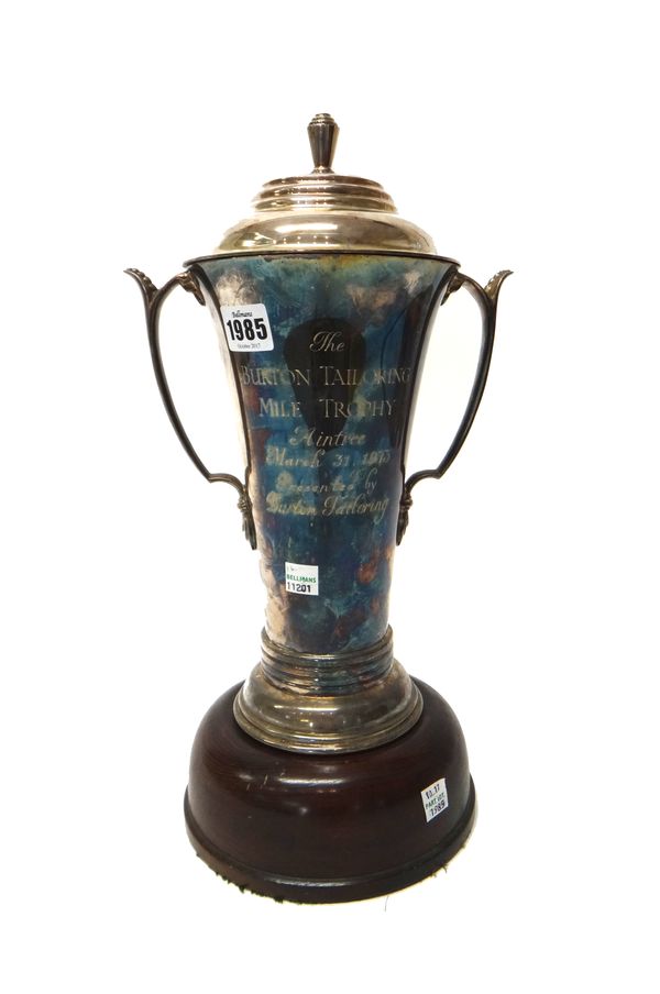 A silver twin handled trophy cup and cover, of tapering cylindrical form and in the Art Deco style, the body presentation engraved, on a circular wood