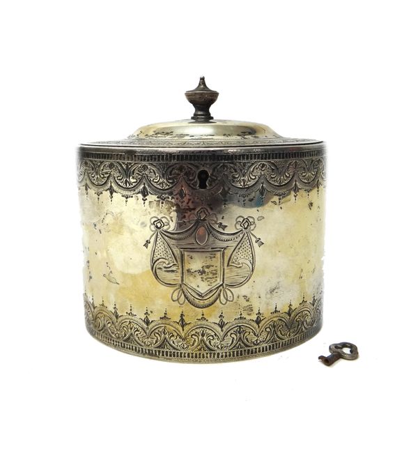 A George III silver tea caddy, of oval lidded form, the body and domed lid with engraved decoration with central shield shaped cartouche, with a key,