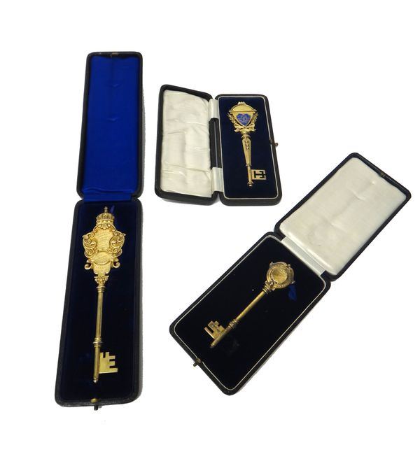 A group of three silver gilt presentation keys, one having a enamelled shield shaped cartouche, each with presentation inscriptions, various dates and