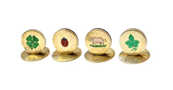 A set of four silver gilt and enamelled place name holders or menu stands, individually enamelled, the motifs comprising; a pig, a vine leaf, a shamro