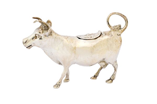 A silver cow creamer, modelled as a standing cow, the looped tail serving as the handle and with a hinged oval cover to the body, import mark London 1