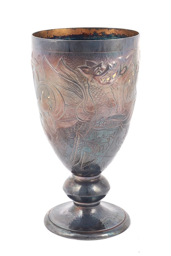 A silver goblet, decorated with royal emblems, including a lion, a dragon and a unicorn, with gilt highlights, raised on a martele decorated circular