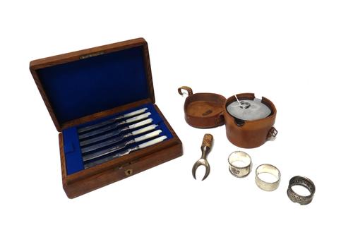 Three silver napkin rings, combined weight 73 gms, a silver topped cork bottle mount, a set of six pairs of plated dessert knives and forks, having mo