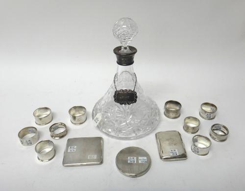 Silver and silver mounted wares, comprising; a faceted glass ships decanter, with a decanter label detailed Port, two cigarette cases and nine napkin