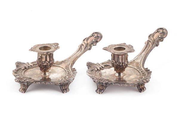 A pair of George III silver chamber candlesticks, each of shaped form, with a rococo border, raised on four scrolled feet and with a detachable sconce