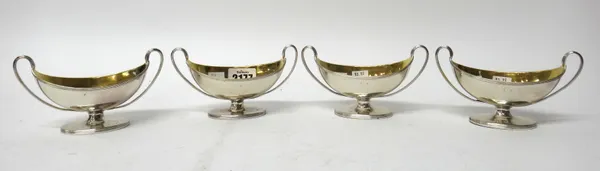 A set of four George III silver twin handled salts, each of boat shaped form, with a reeded handle and raised on an oval foot, later gilded within, Lo