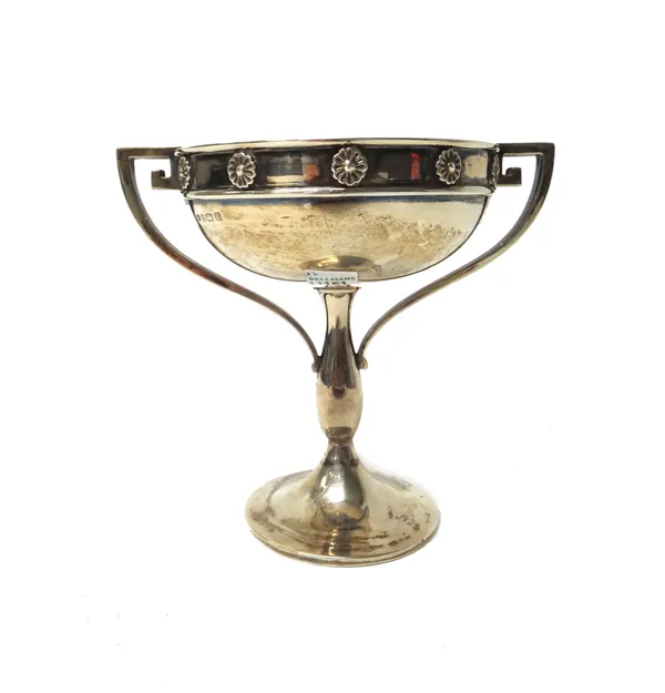 A silver twin handled bowl, the rim decorated with flowerhead shaped motifs, between angular handles, raised on a circular trumpet shaped foot, height