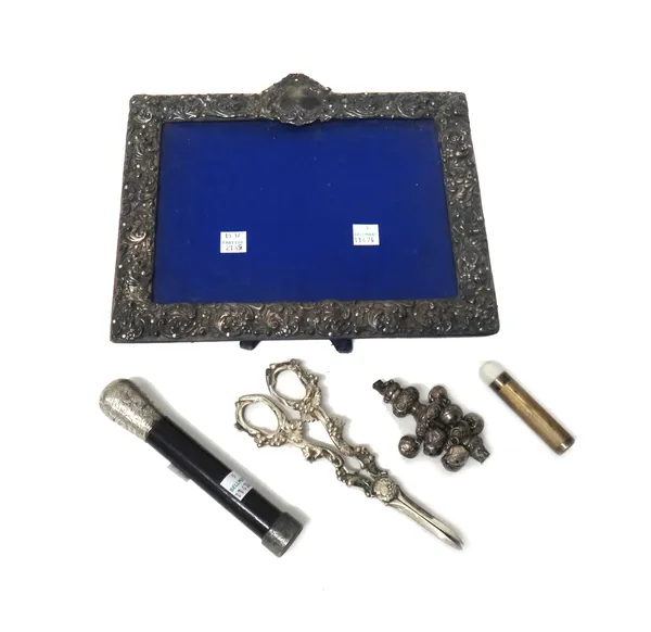 A silver mounted shaped rectangular photograph frame, a baby's rattle fitted with nine bells, a silver mounted small torch case, a silver mounted ebon