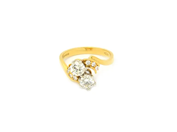 An 18ct gold and diamond ring, claw set with the two principal circular cut diamonds at the centre, between diamond three stone curved shoulders, in a