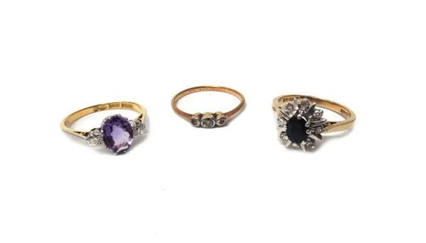 A gold and platinum, amethyst and diamond three stone ring, claw set with the oval cut amethyst between two circular cut diamonds, detailed 18 CT PLAT