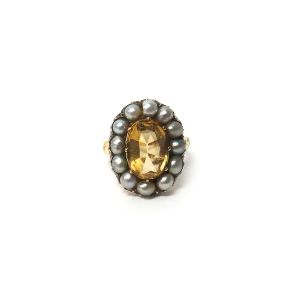 A gold, topaz and half pearl set oval cluster ring, mounted with the oval cut topaz at the centre within a surround of half pearls, ring size N and a