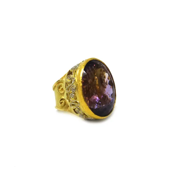 A gold and platinum ring, collet set with a large oval cut amethyst, the mount with applied and pierced scrollwork decoration, detailed '750 PT', bear