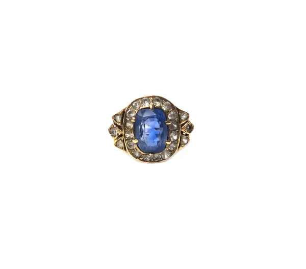 A gold, sapphire and colourless gem set cluster ring, claw set with the oval cut Ceylon sapphire at the centre, within a surround of circular cut colo