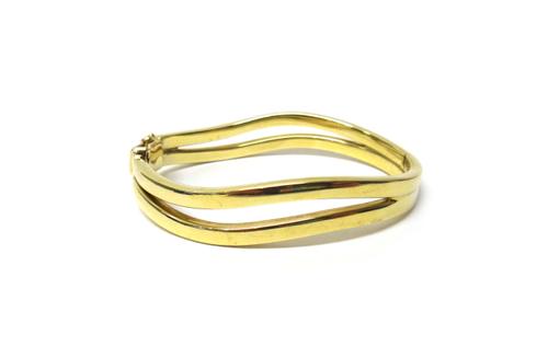 A 9ct gold oval hinged bangle, in a two row curved abstract design, on a snap clasp, with a foldover safety catch, gross weight 15.6 gms, with a case.