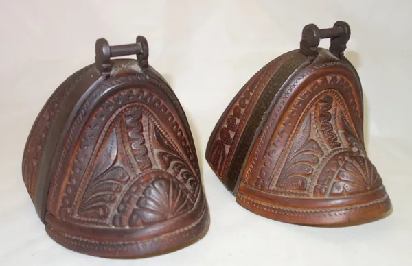 A pair of hardwood and steel bound enclosed stirrups, early 20th century, possibly South American, each with carved foliate decoration, 12.5cm high, (