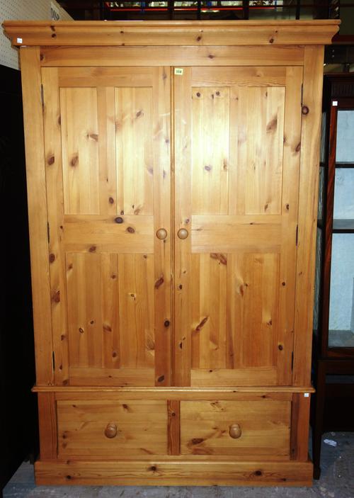 A 20th century pine double wardrobe over a two drawer base, 129cm wide x 204cm high.   M10