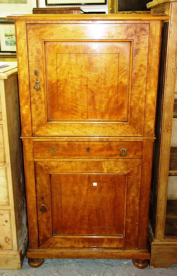 A late 19th century Continental satin birch panelled two door cupboard, on bun feet, 68cm wide x 131cm high.    F9