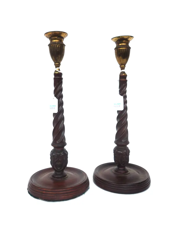 A pair of Georgian style mahogany candlesticks, early 20th century, each with brass sconce and carved barleytwist stem, on a loaded circular base, 33c